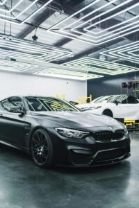 A sleek black luxury car parked in a modern garage with striking lighting design.