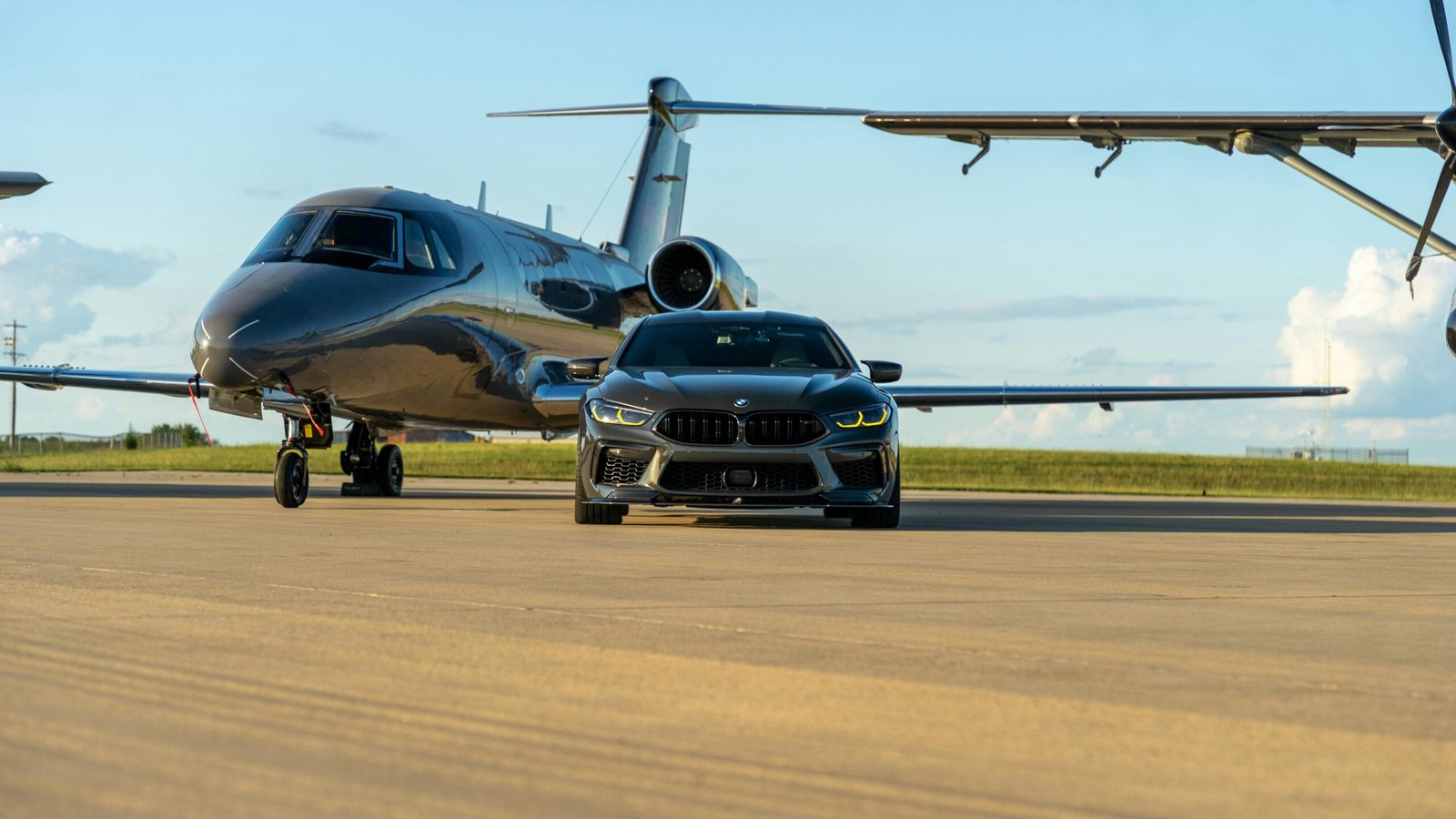 A sleek luxury car parked in front of a private jet on a runway, capturing opulence.