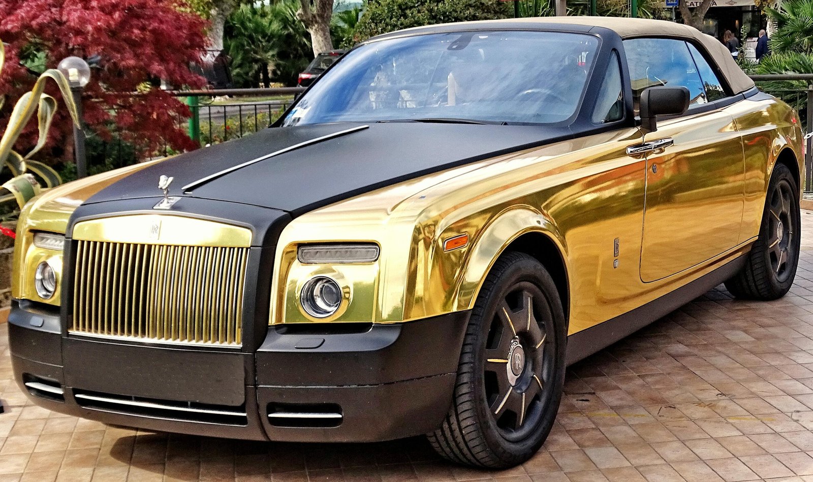 Stunning gold Rolls Royce Phantom Drophead Coupe parked outdoors in Sirmione, Italy.