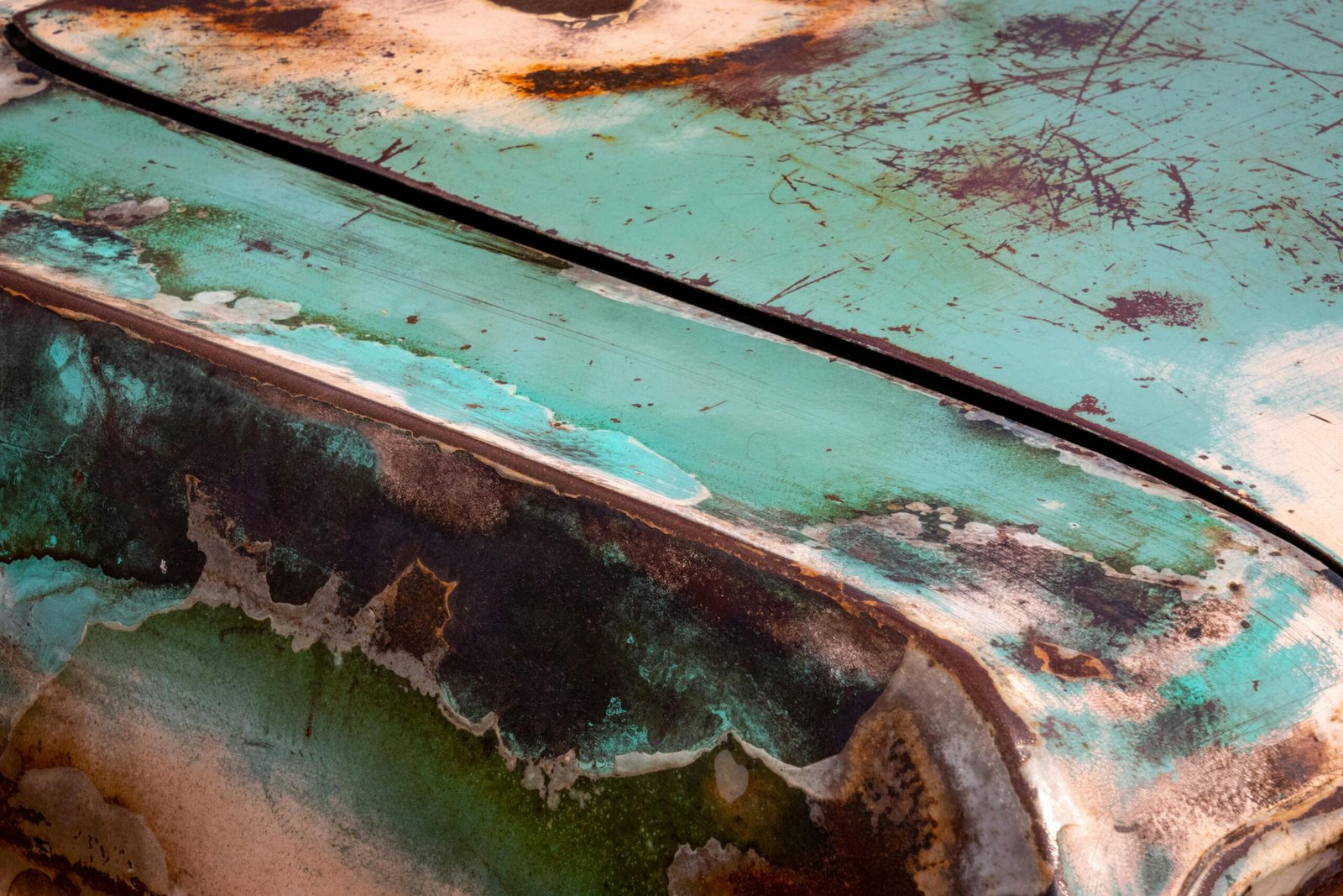 Detailed close-up of a rusty vintage car fender with peeling paint.